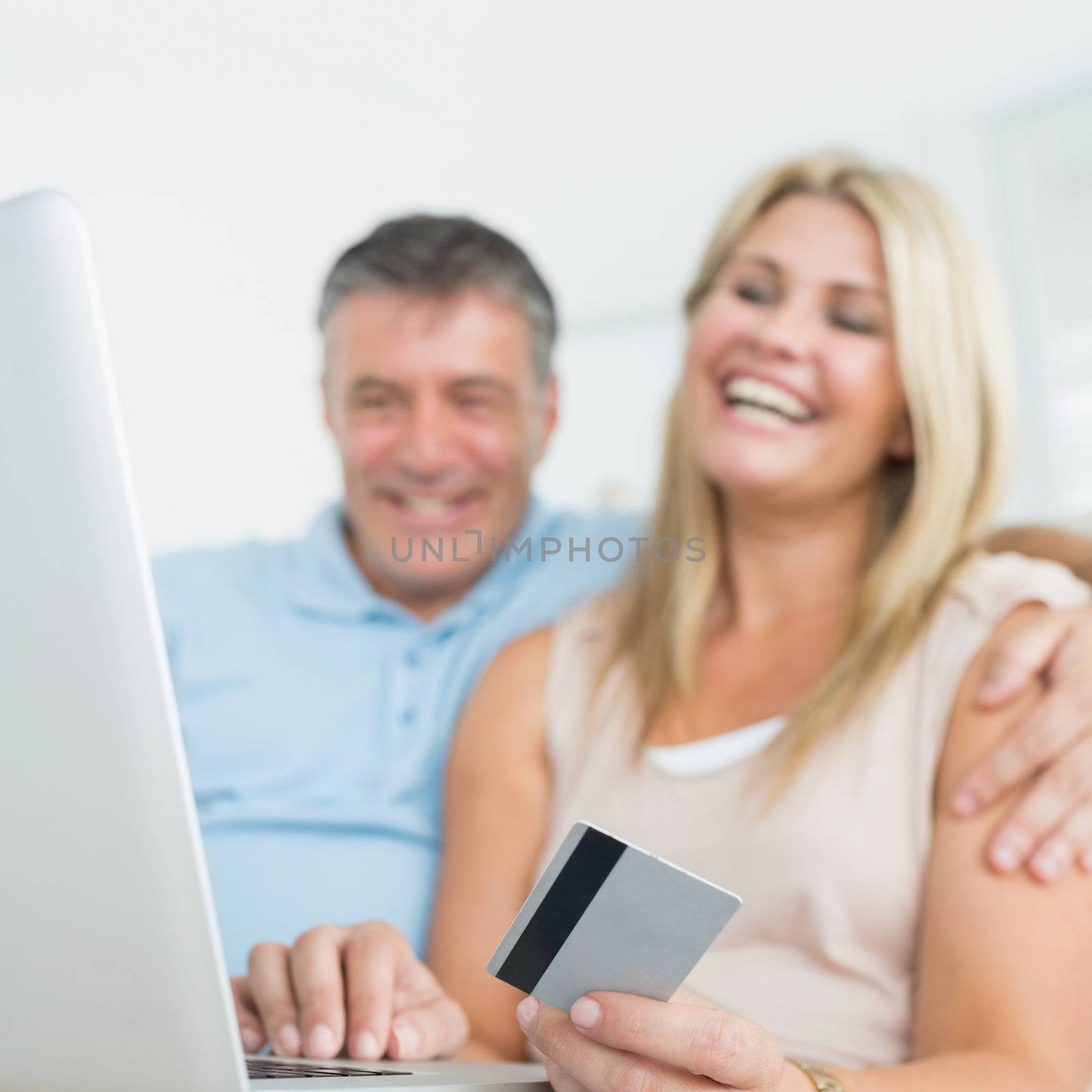 Happy couple using laptop on the sofa to chop online
