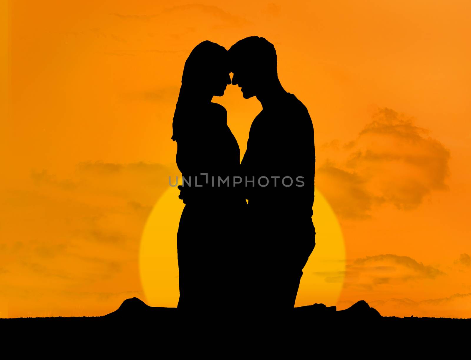 Silhouette of couple embracing under a sunset kneeling face to face