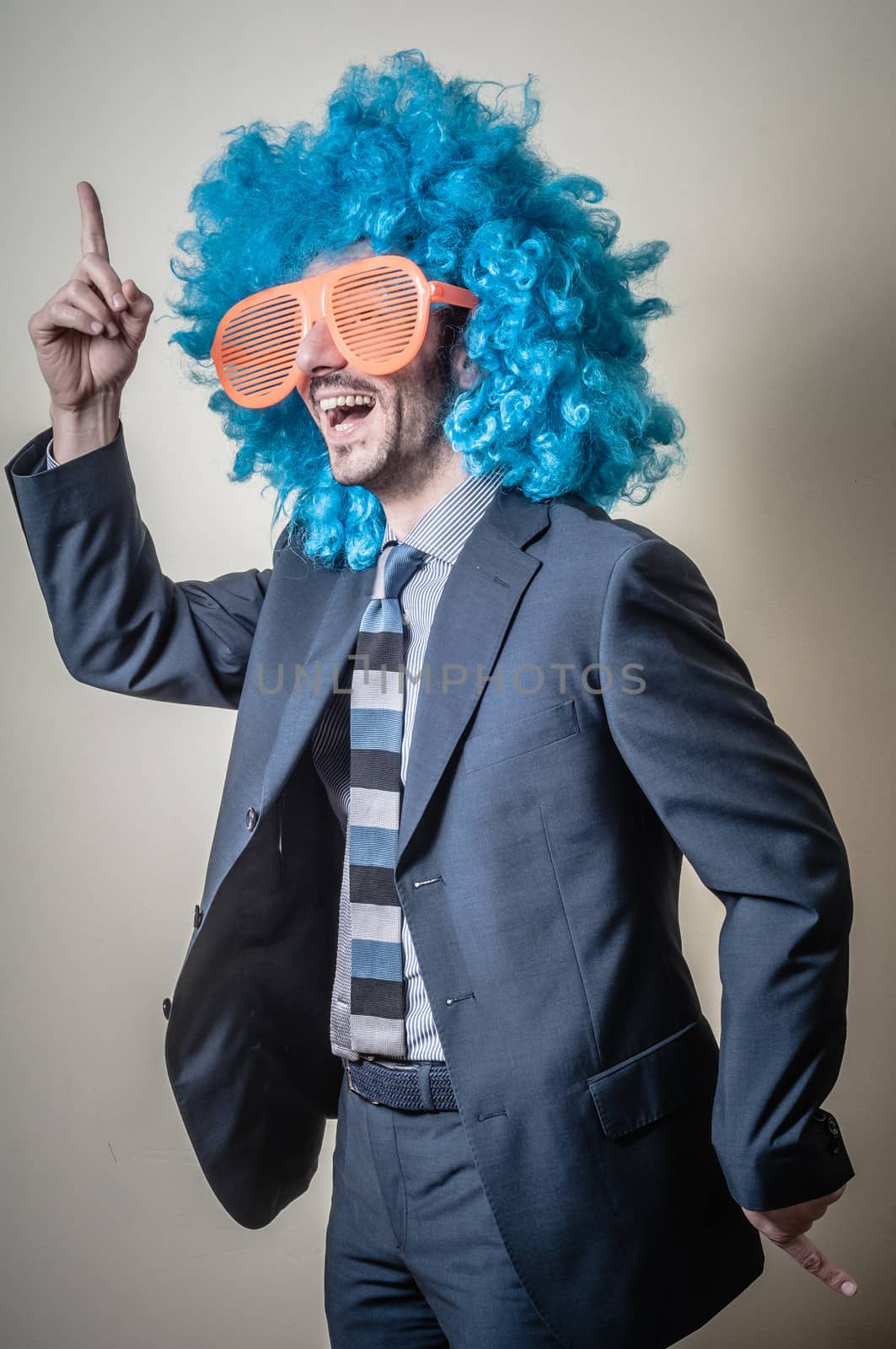 funny businessman with big orange glasses and blue wig on gray background