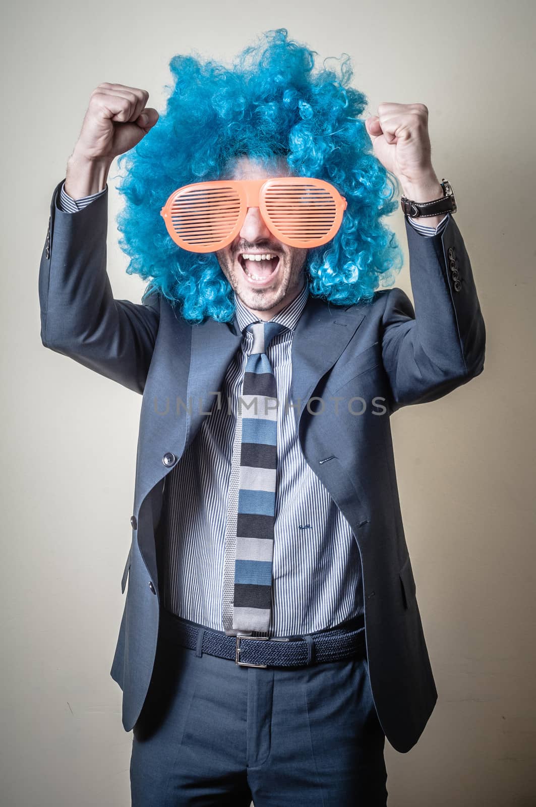 funny businessman with big orange glasses and blue wig on gray background