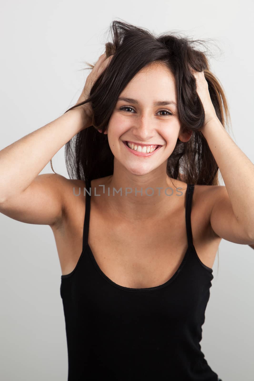 Beautiful young woman playing in her hair by Izaphoto