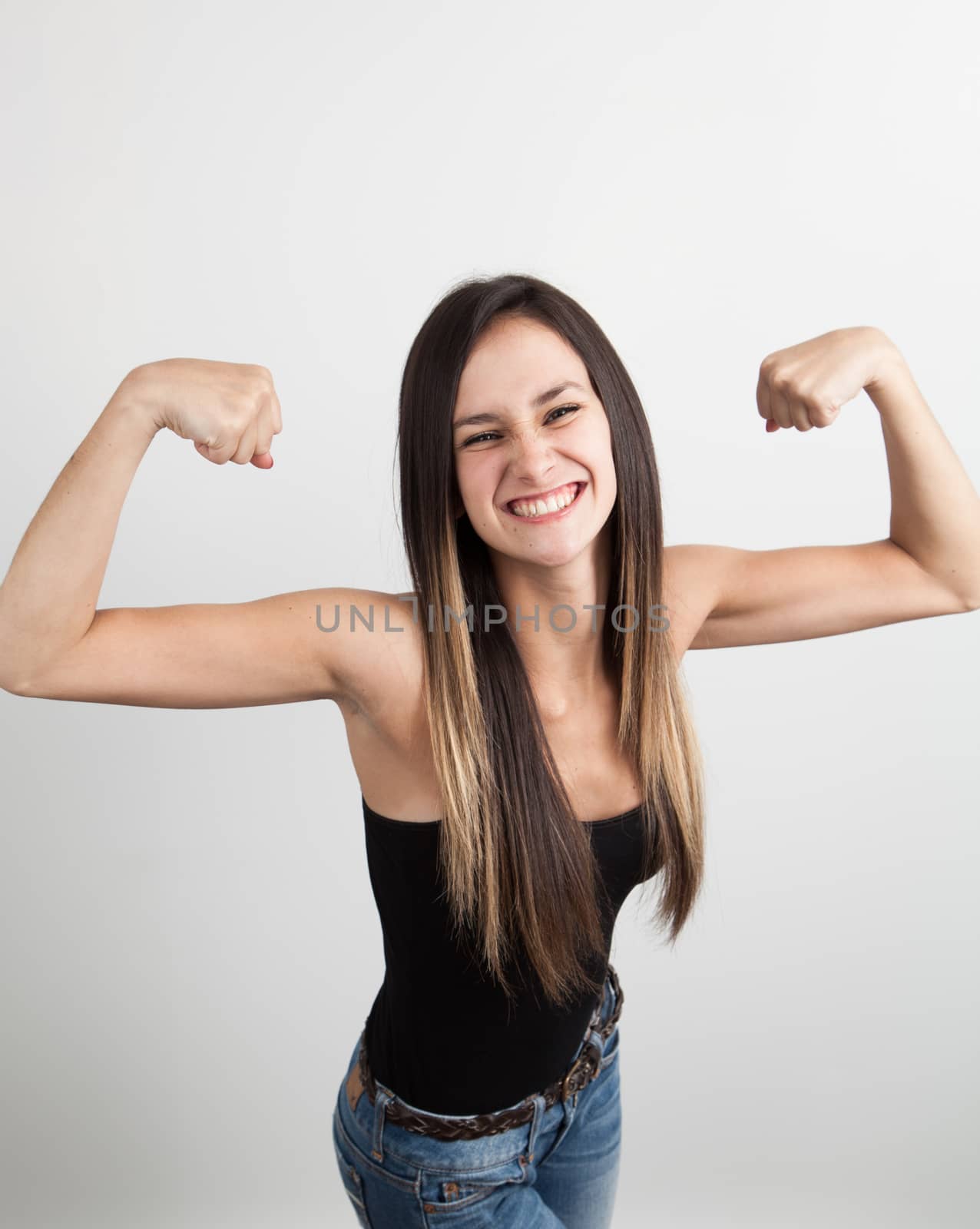 Beautiful young woman flexing her biceps by Izaphoto