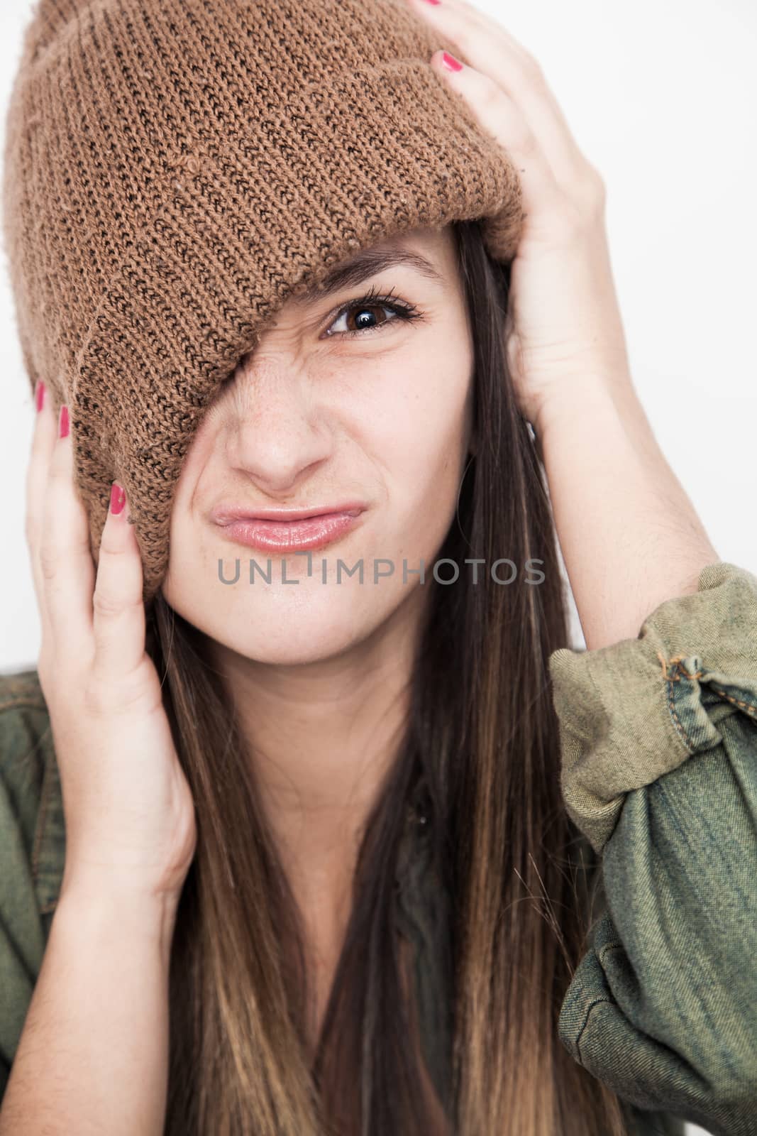 Young brunette woman doing funny face with brown hat