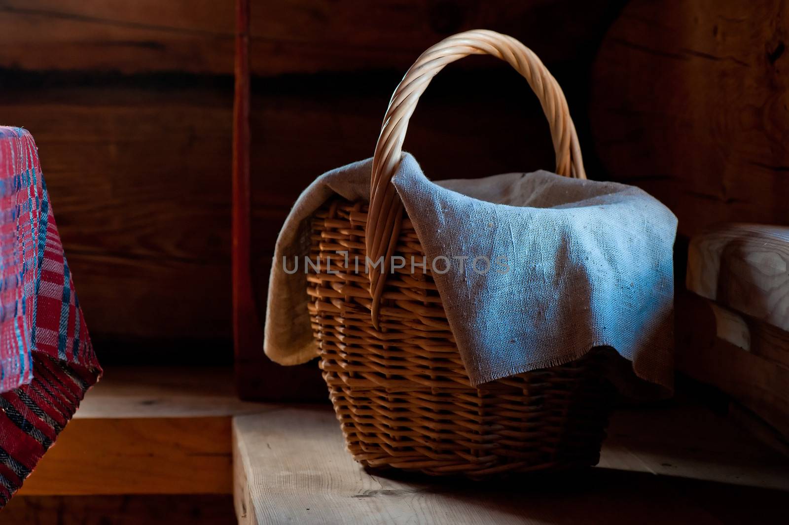 Wicker basket with a towel on a wooden bench in a village house
