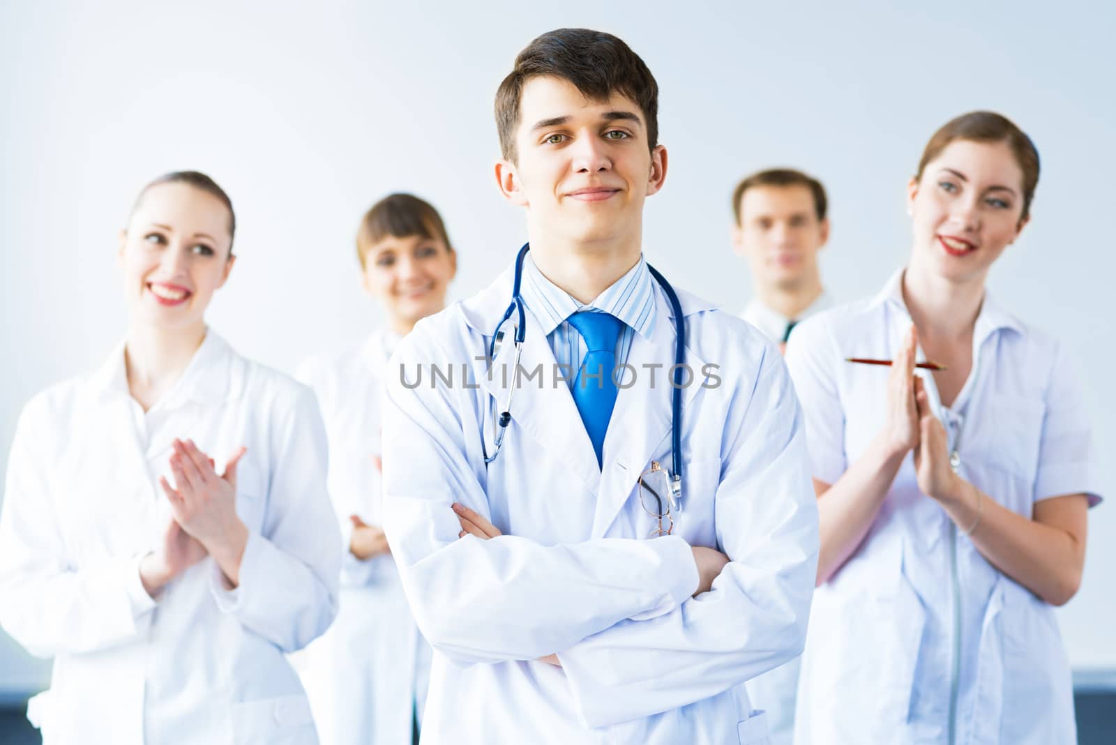 successful doctor, accepts congratulations from colleagues, stand behind him and clap