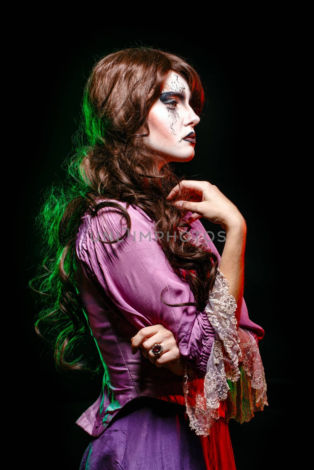 Girl in the image of a witch with a theatrical make-up in studio shot