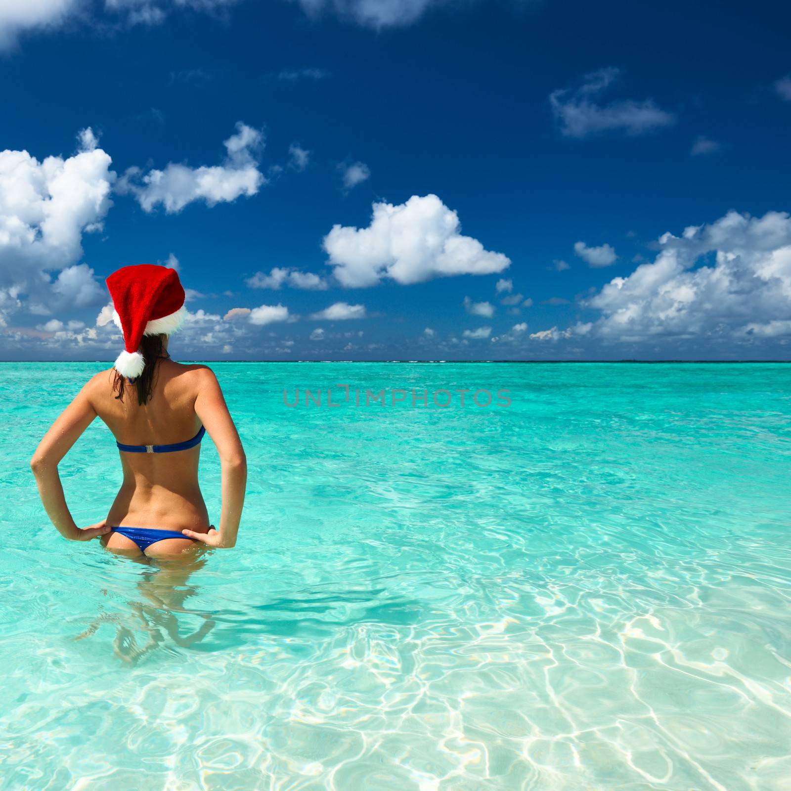 Woman in santa's hat in bikini at tropical beach