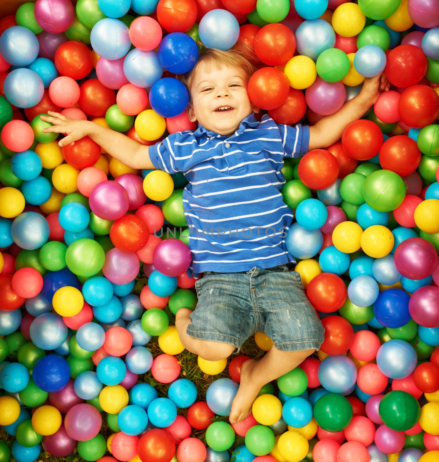 Happy child playing at colorful plastic balls playground high view