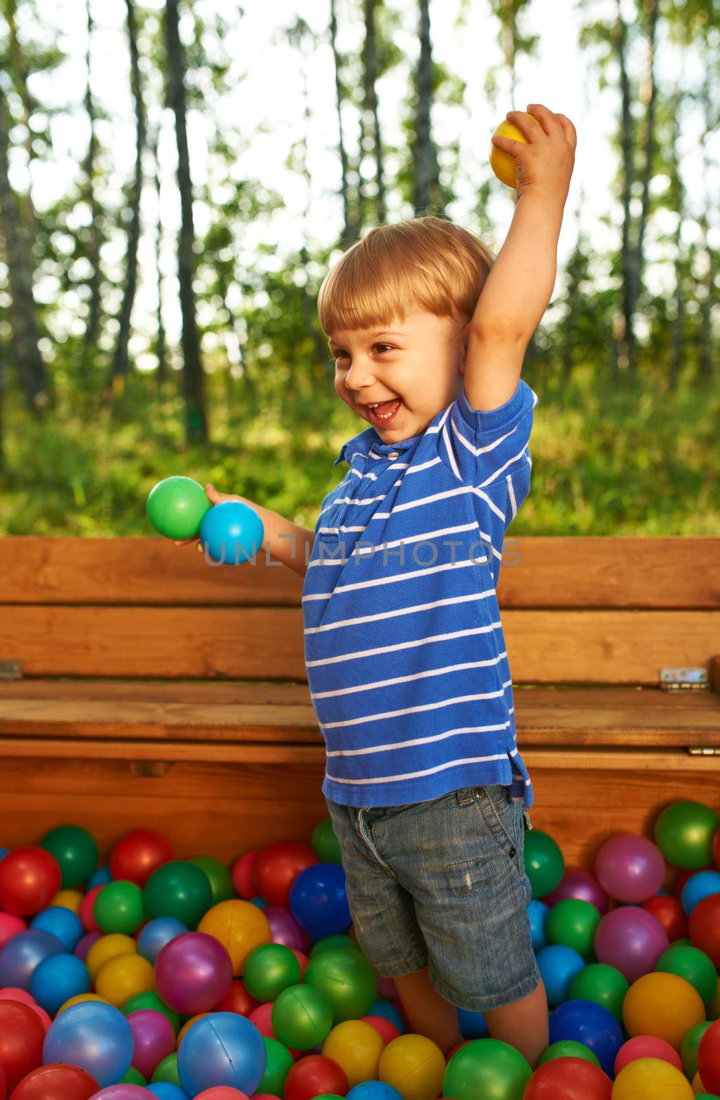 Happy child playing with colorful plastic balls by haveseen