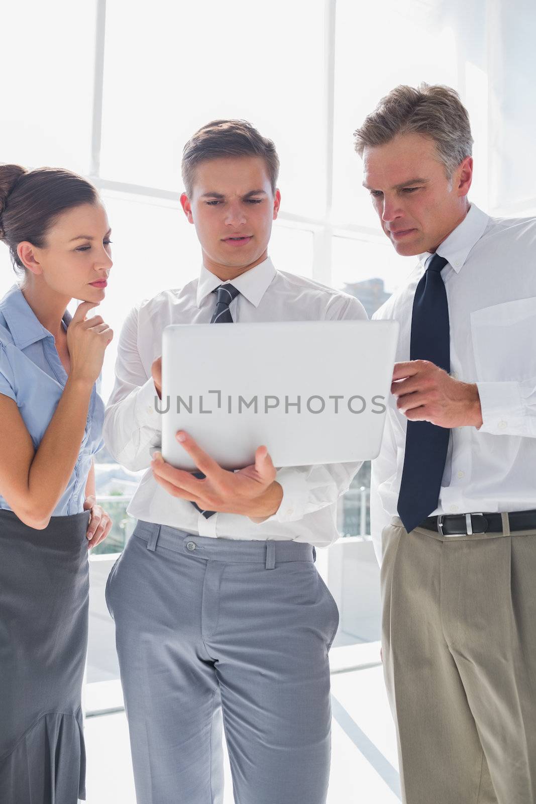 Three business people using a laptop while working in a bright office