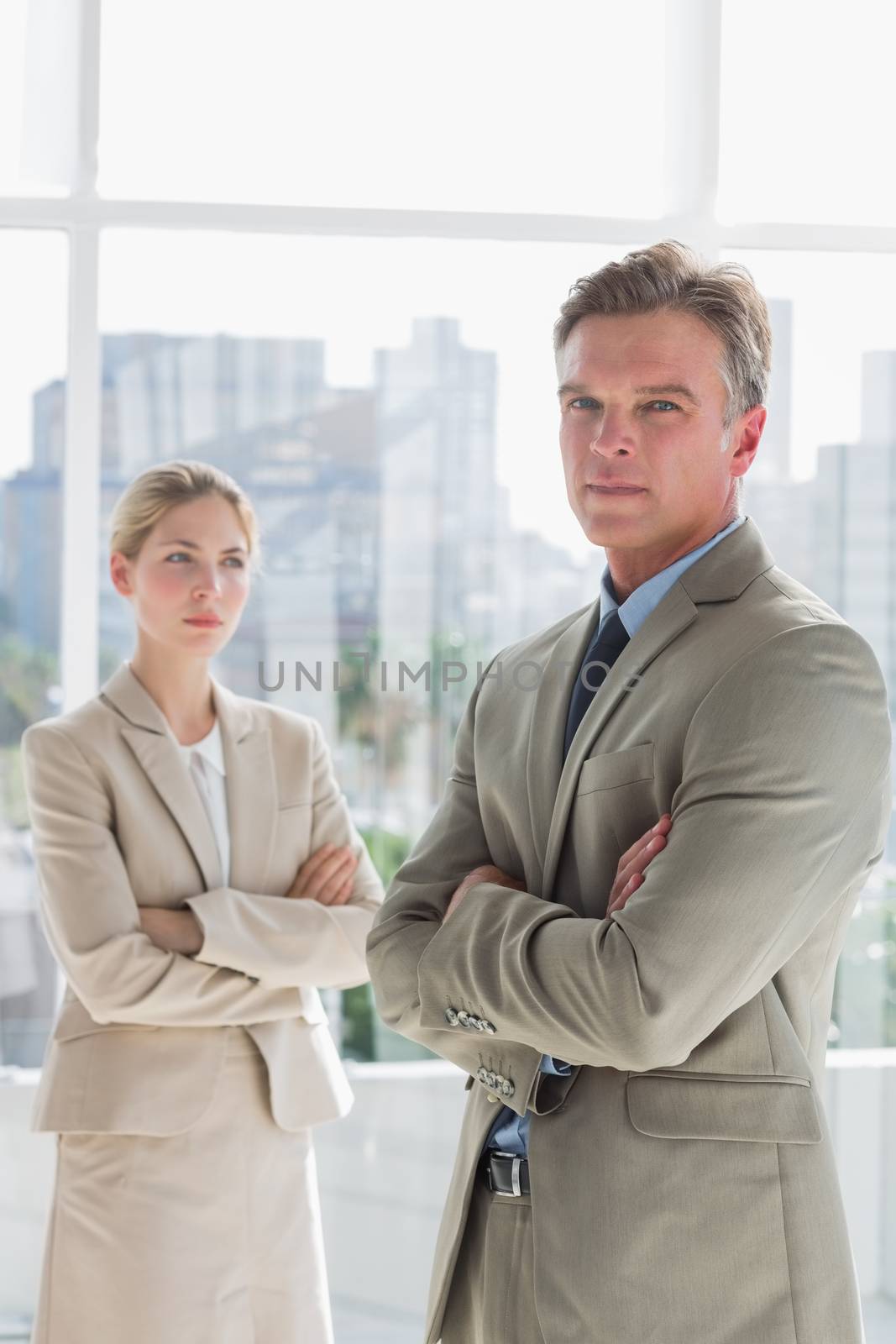 Business people standing with arms crossed in a bright office