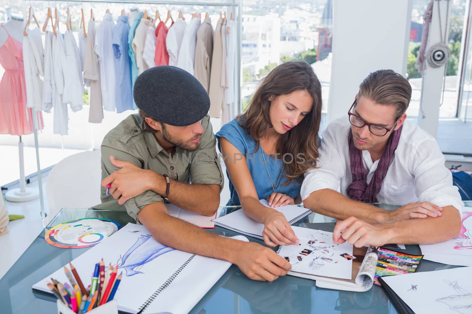 Three fashion designers working on desk in a bright office