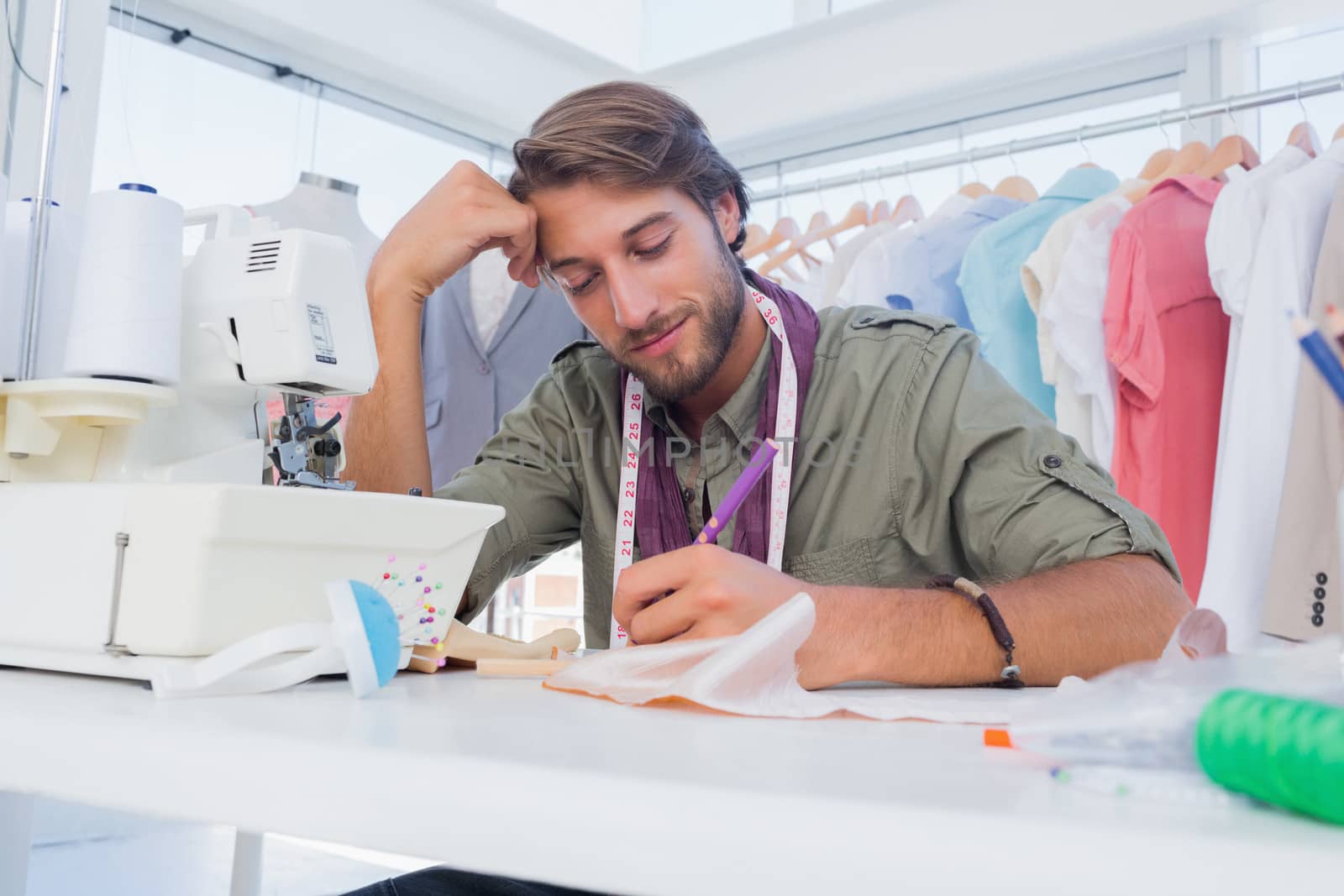 Smiling fashion designer working at his desk in a creative office