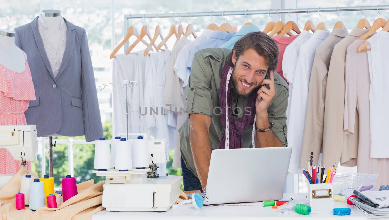 Smiling fashion designer using laptop and calling