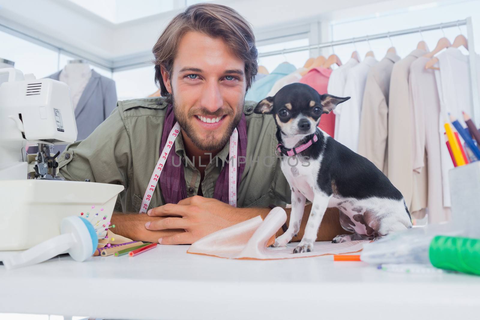 Fashion designer looking at camera with his chihuahua sitting on desk