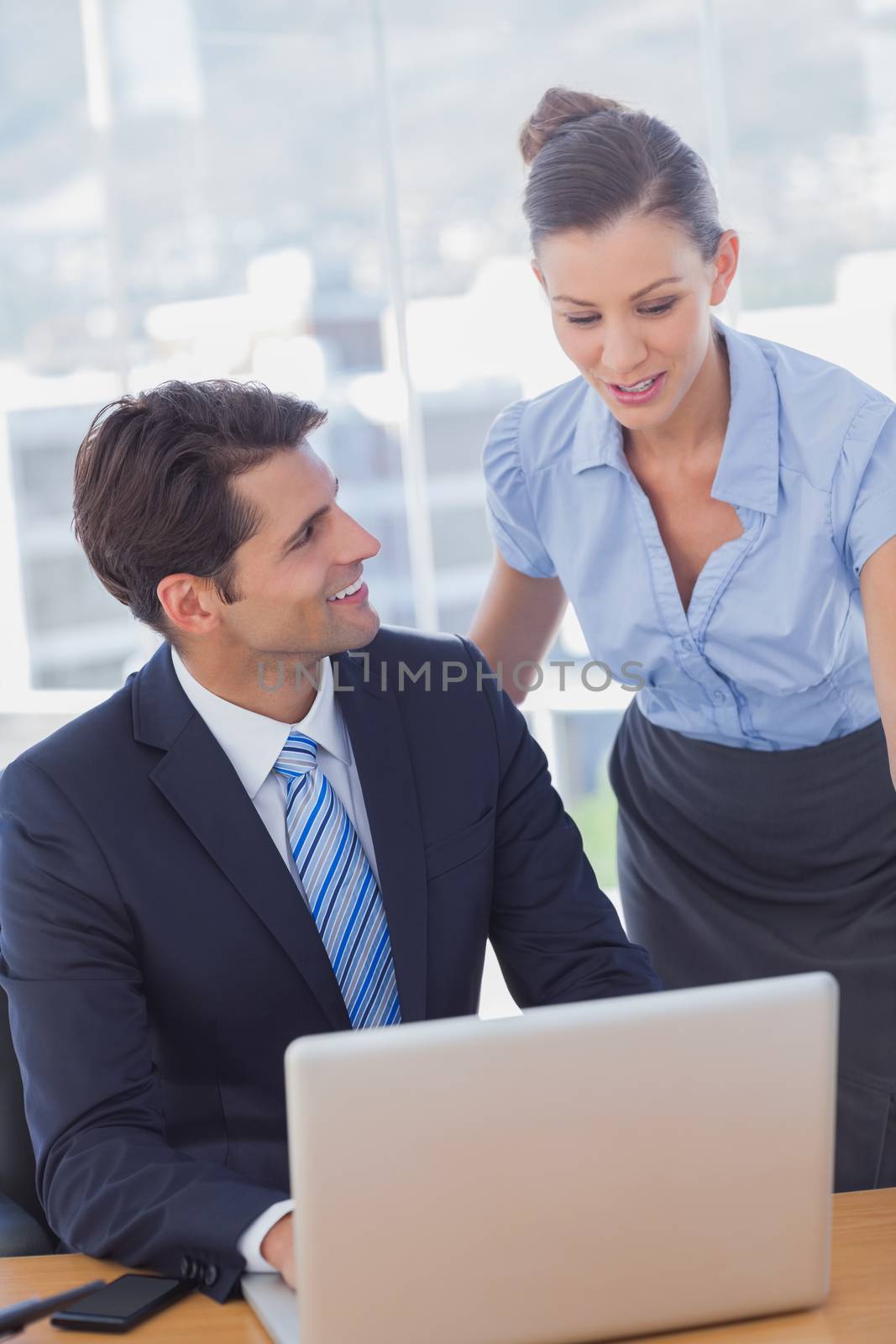 Happy business people working together with a laptop and smiling  by Wavebreakmedia