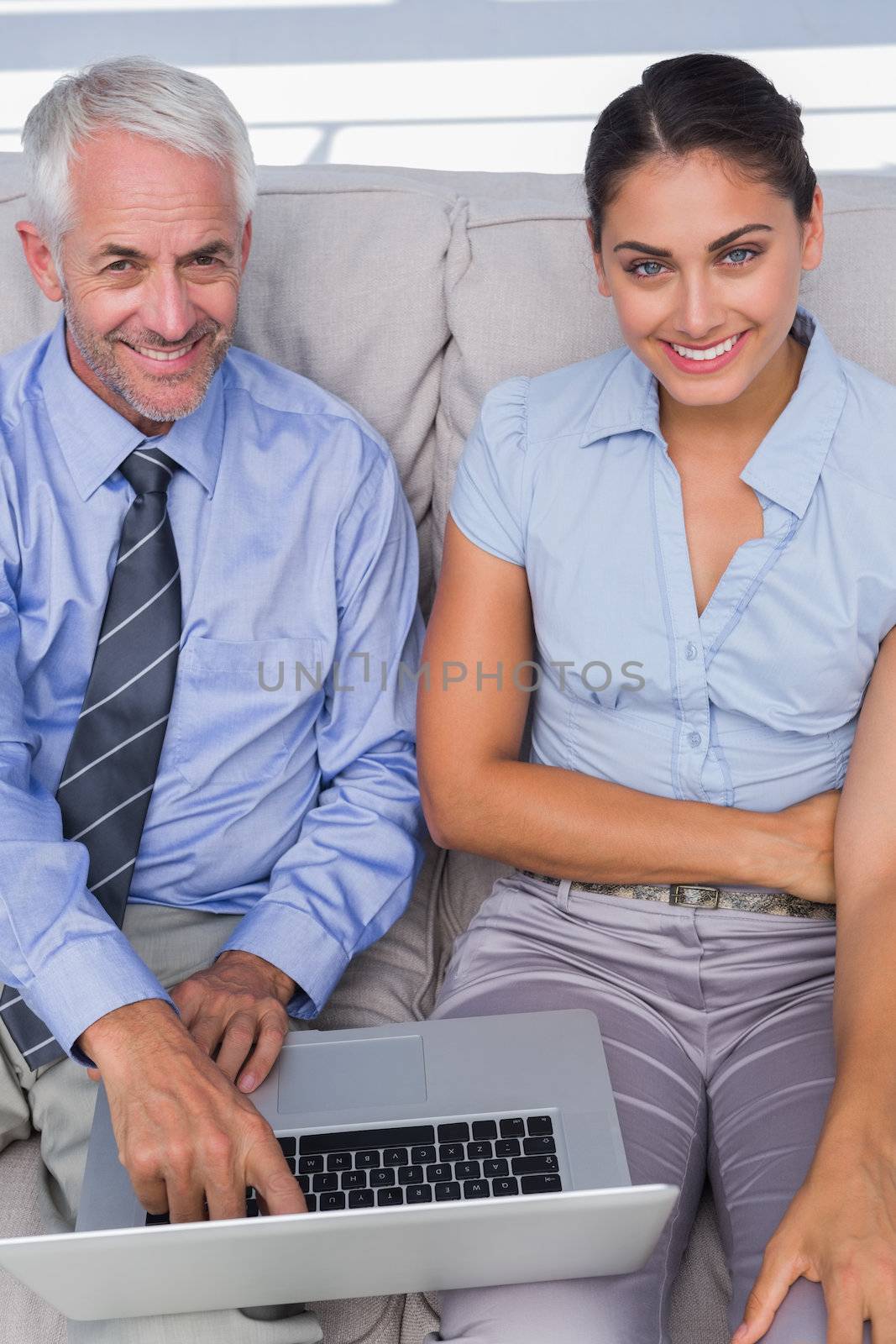 Business people using laptop on the couch and smiling up at camera by Wavebreakmedia