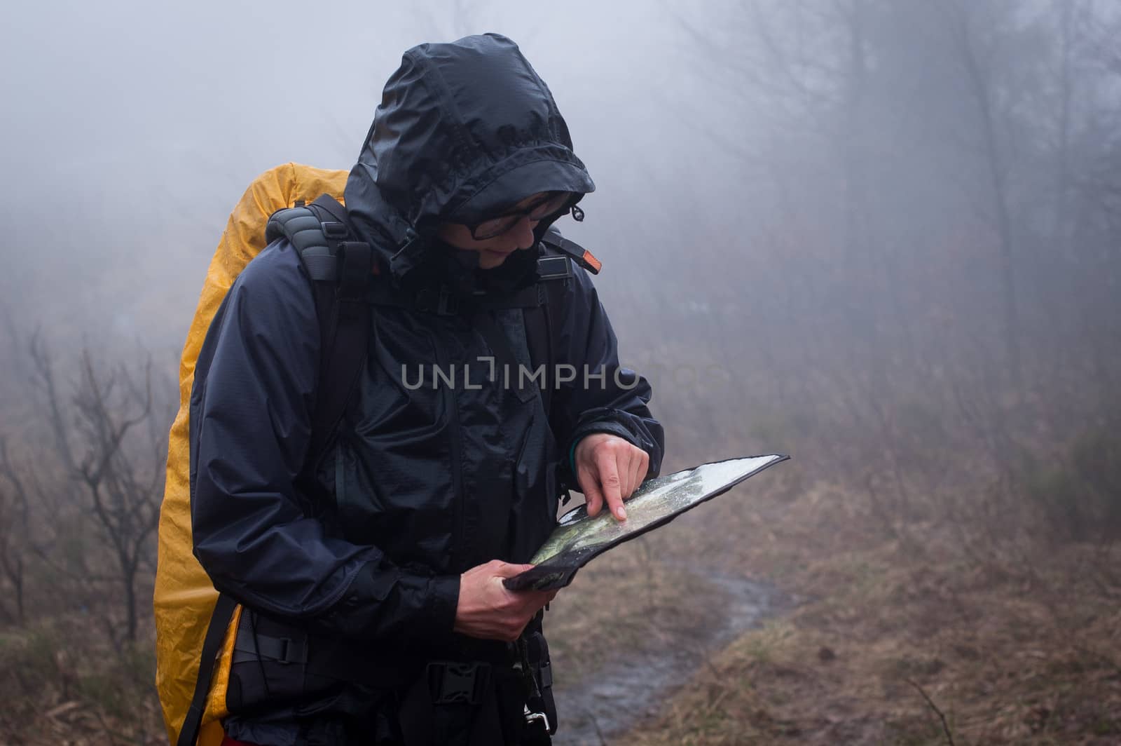 Young woman reading a map in the misty evening