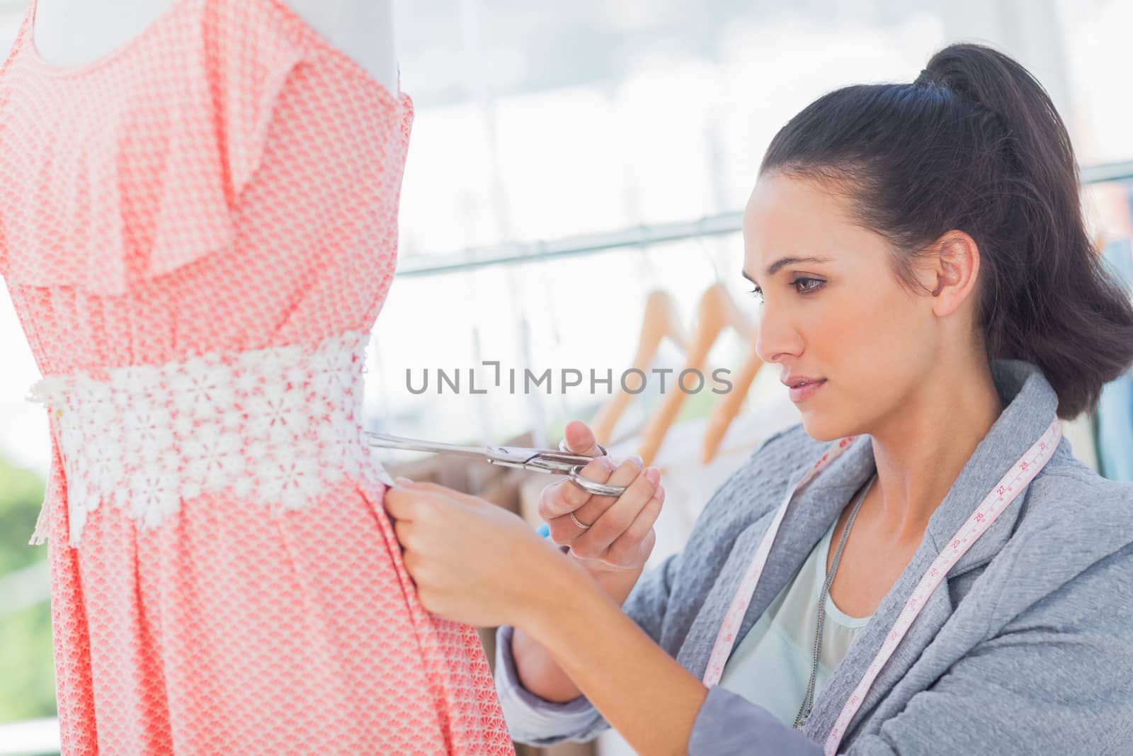 Attractive fashion designer cutting dress by Wavebreakmedia