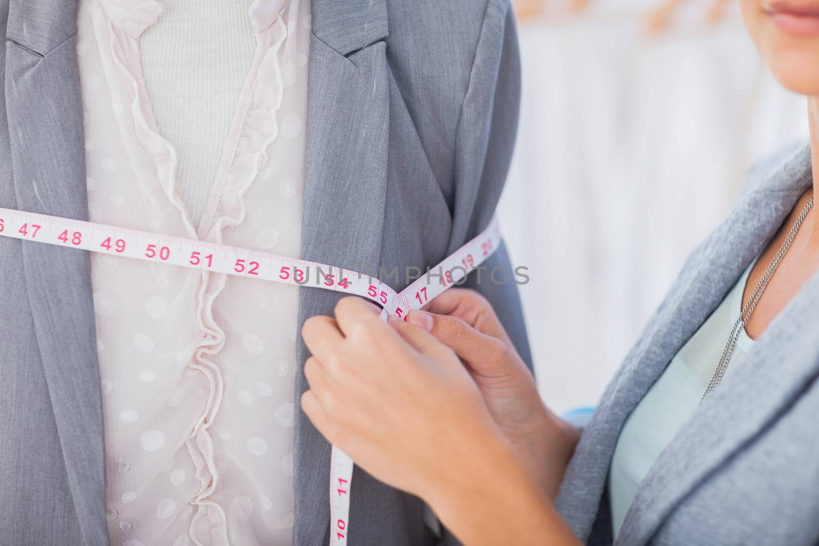 Fashion designer measuring blazer with measuring tape