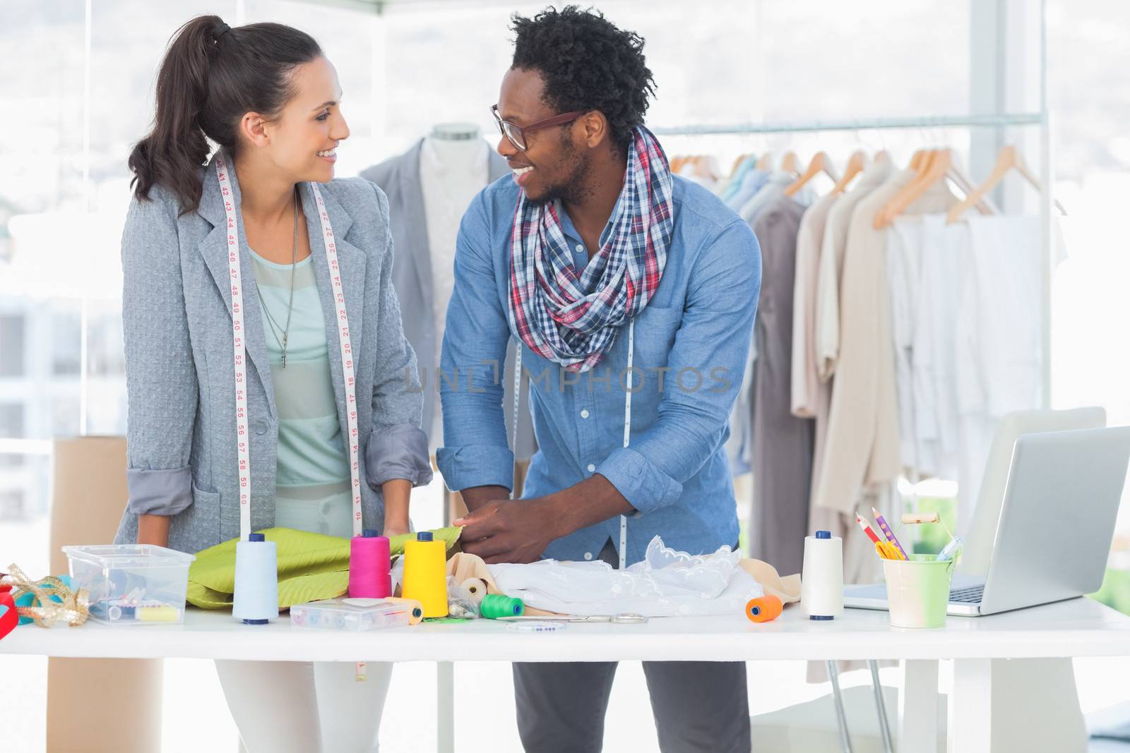 Smiling fashion designers working together in a bright studio