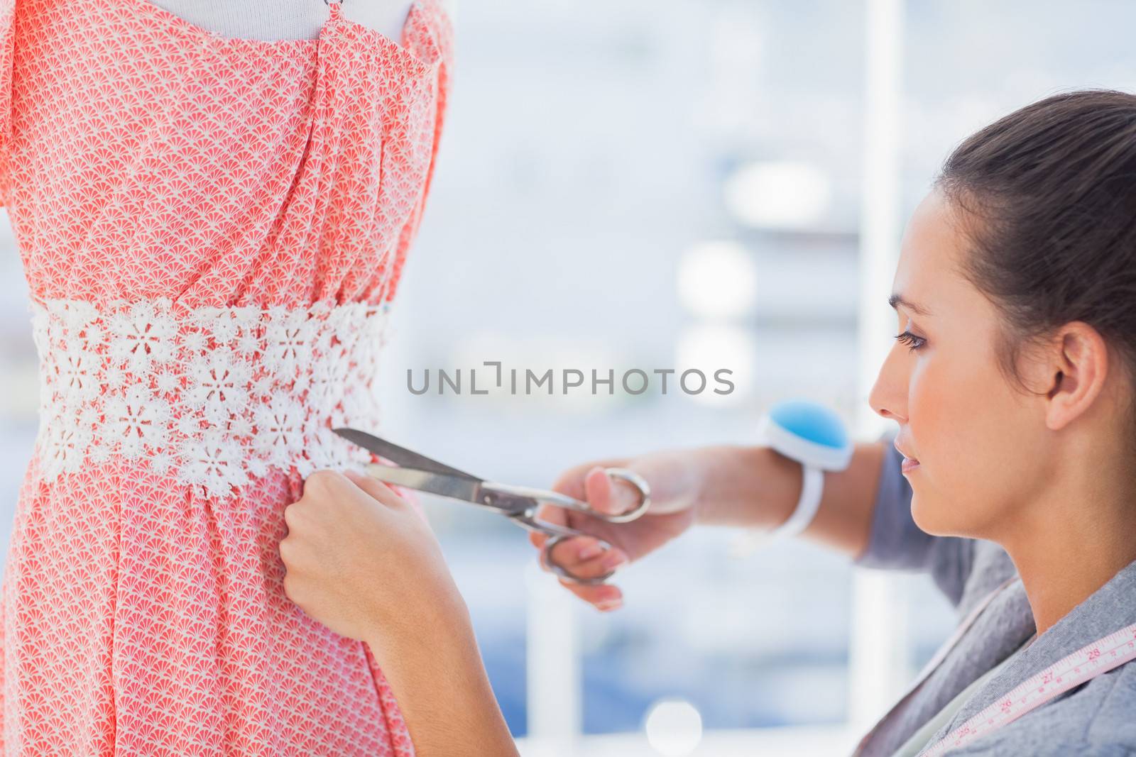 Fashion designer cutting dress with scissors