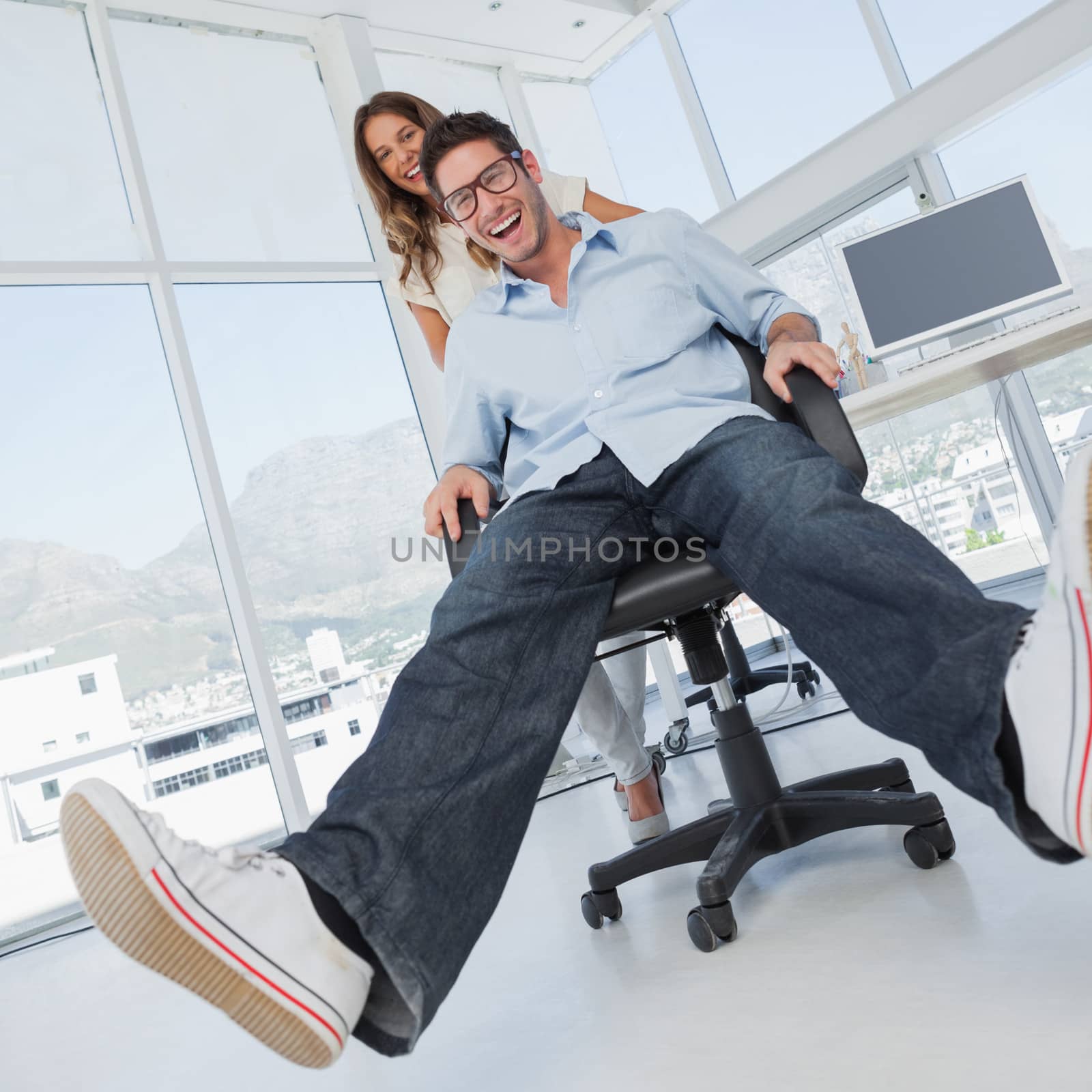 Smiling designers having fun with on a swivel chair by Wavebreakmedia