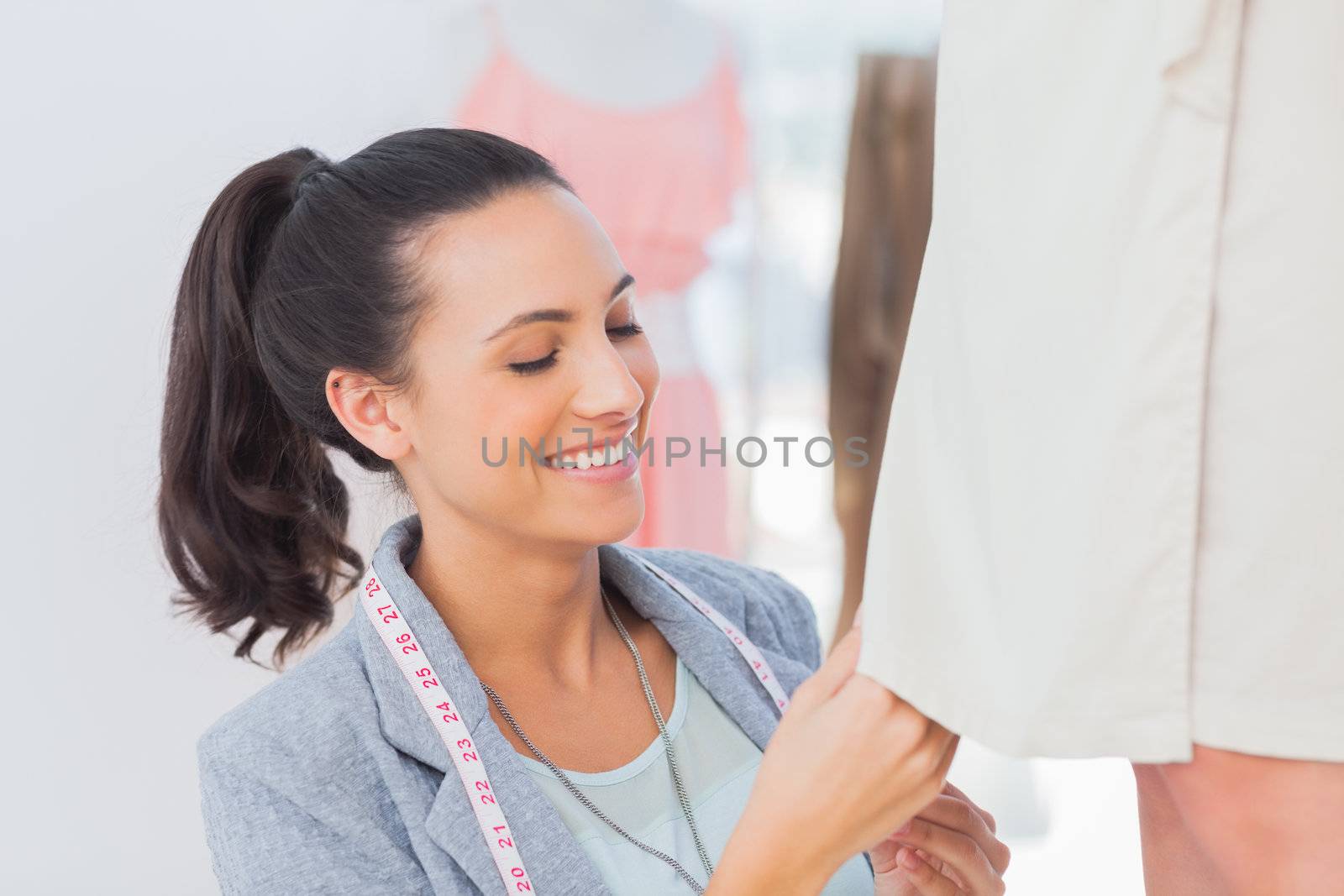 Happy fashion designer adjusting dress on a model