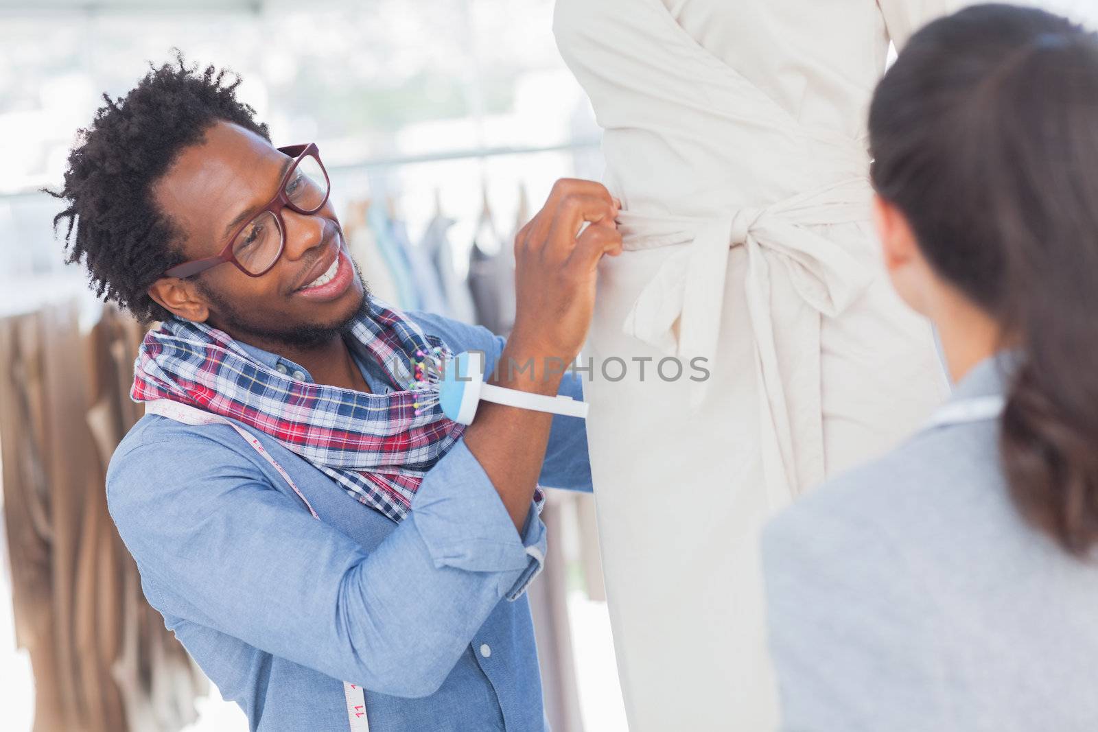 Cheerful fashion designers standing next to a model and adjusting a dress