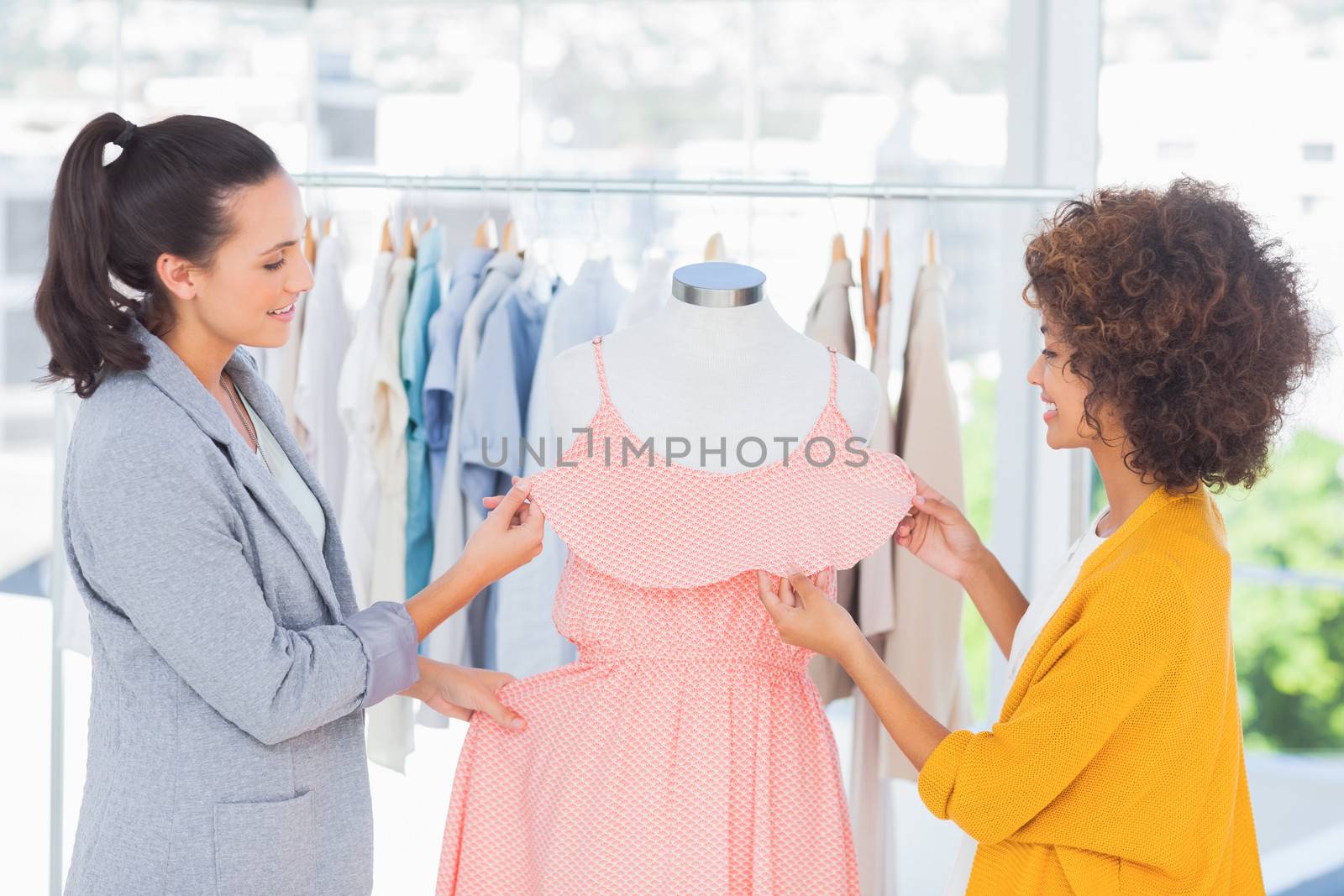 Attractive fashion designers adjusting a dress on a mannequin