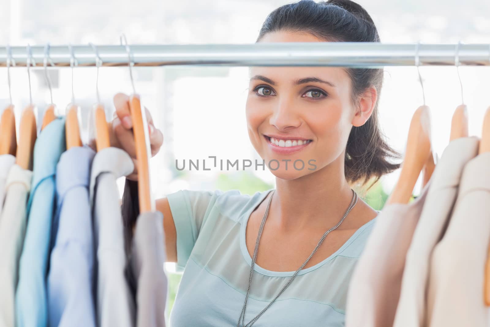 Smiling fashion designer looking at clothes in her studio
