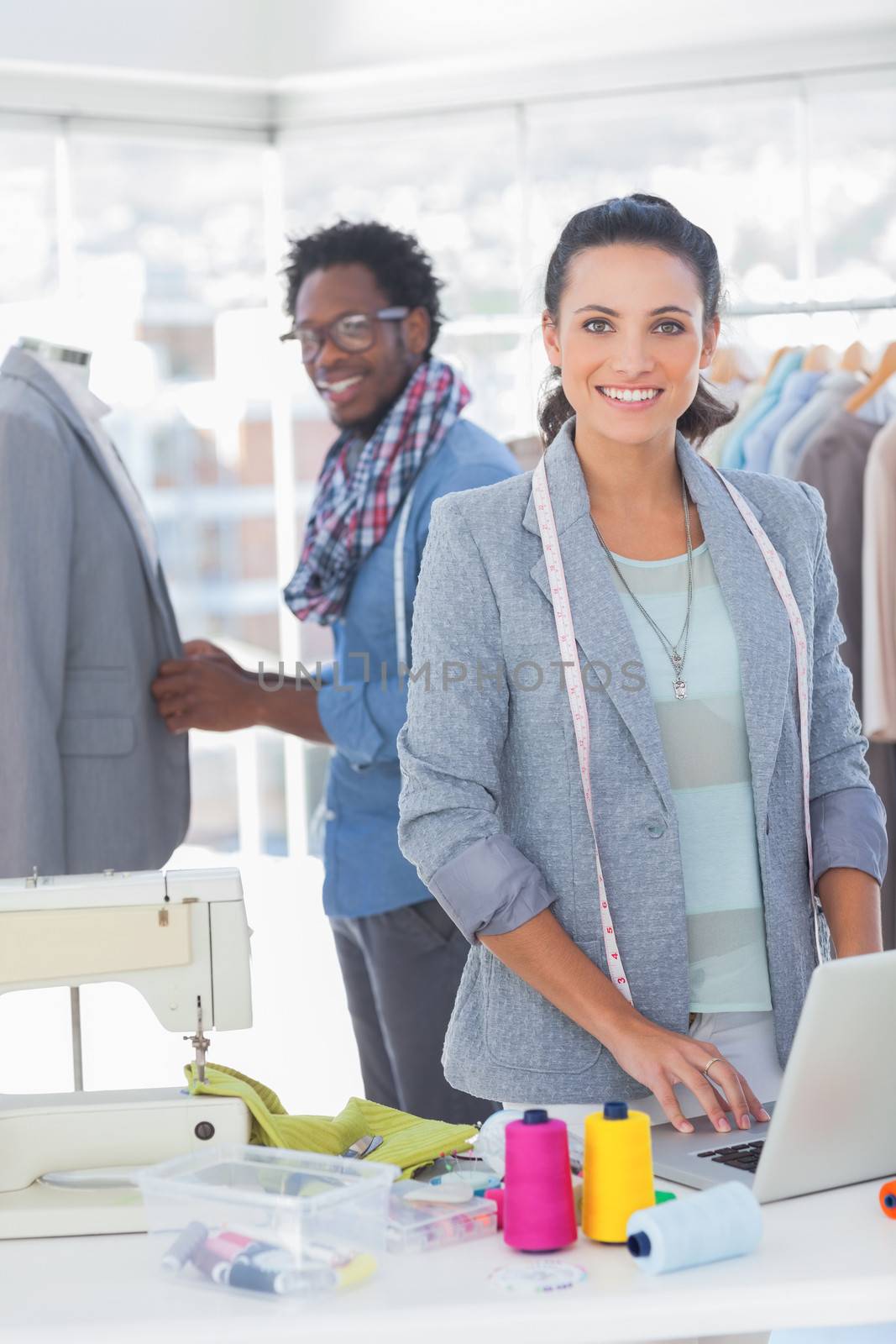 Team of fashion designers working and smiling at camera in bright studio