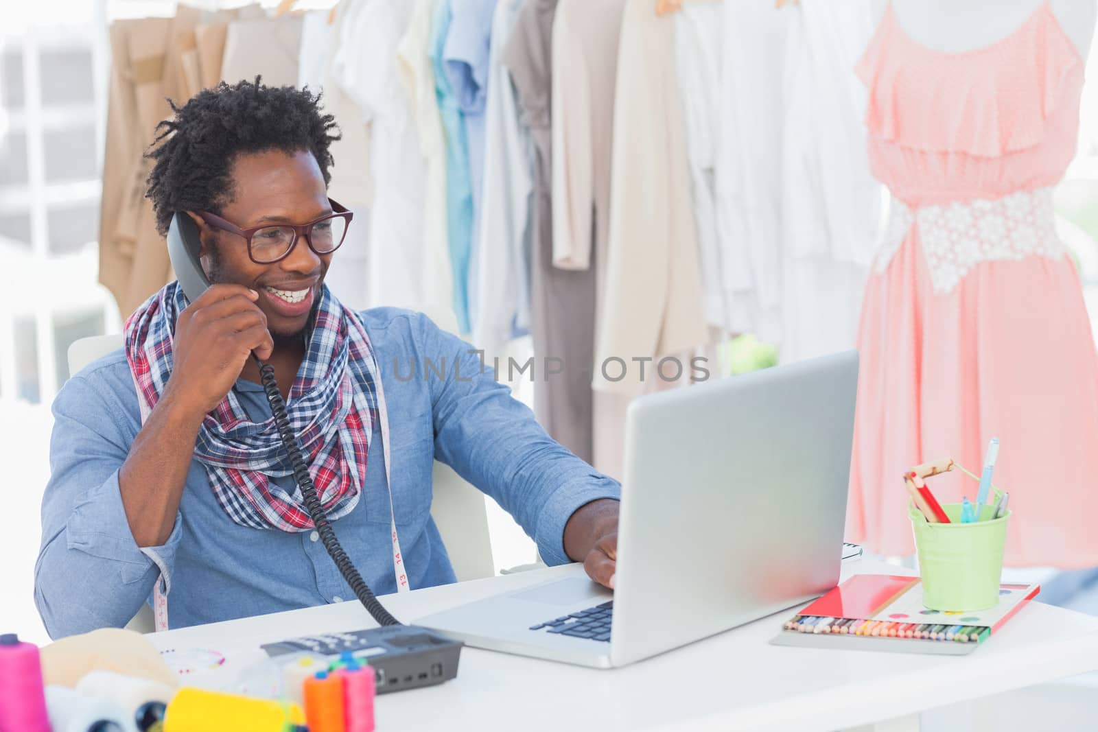Attractive fashion designer speaking on the phone in a creative office