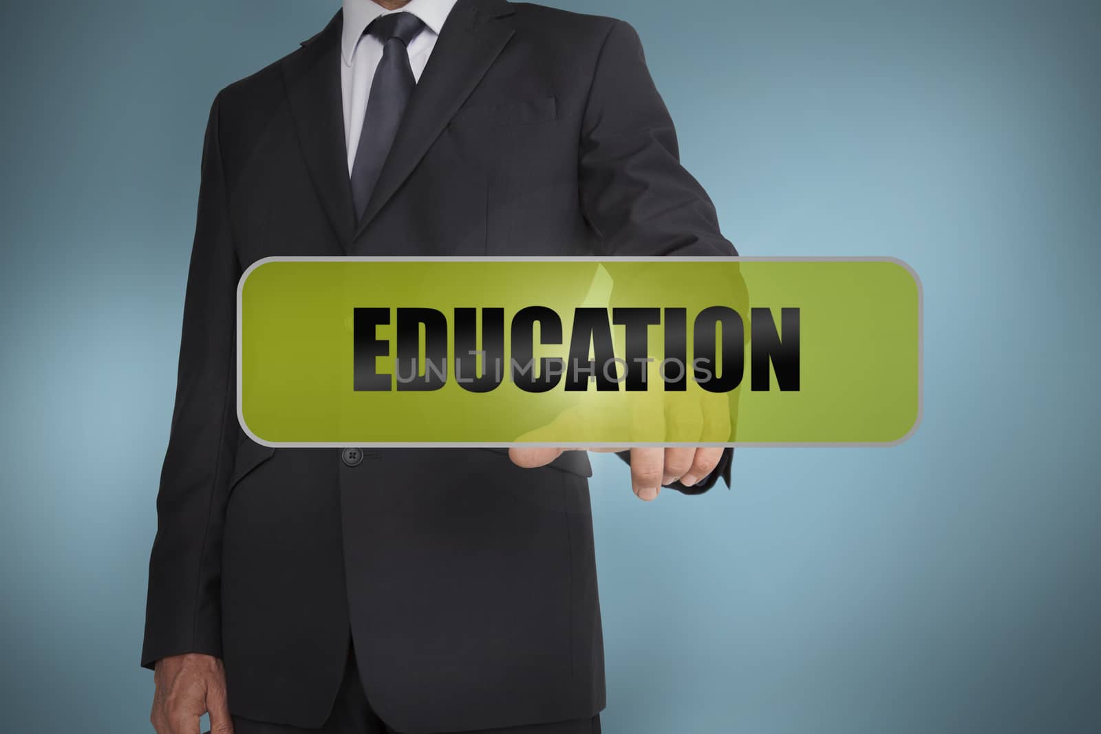 Businessman touching the word education written on green tag on blue background