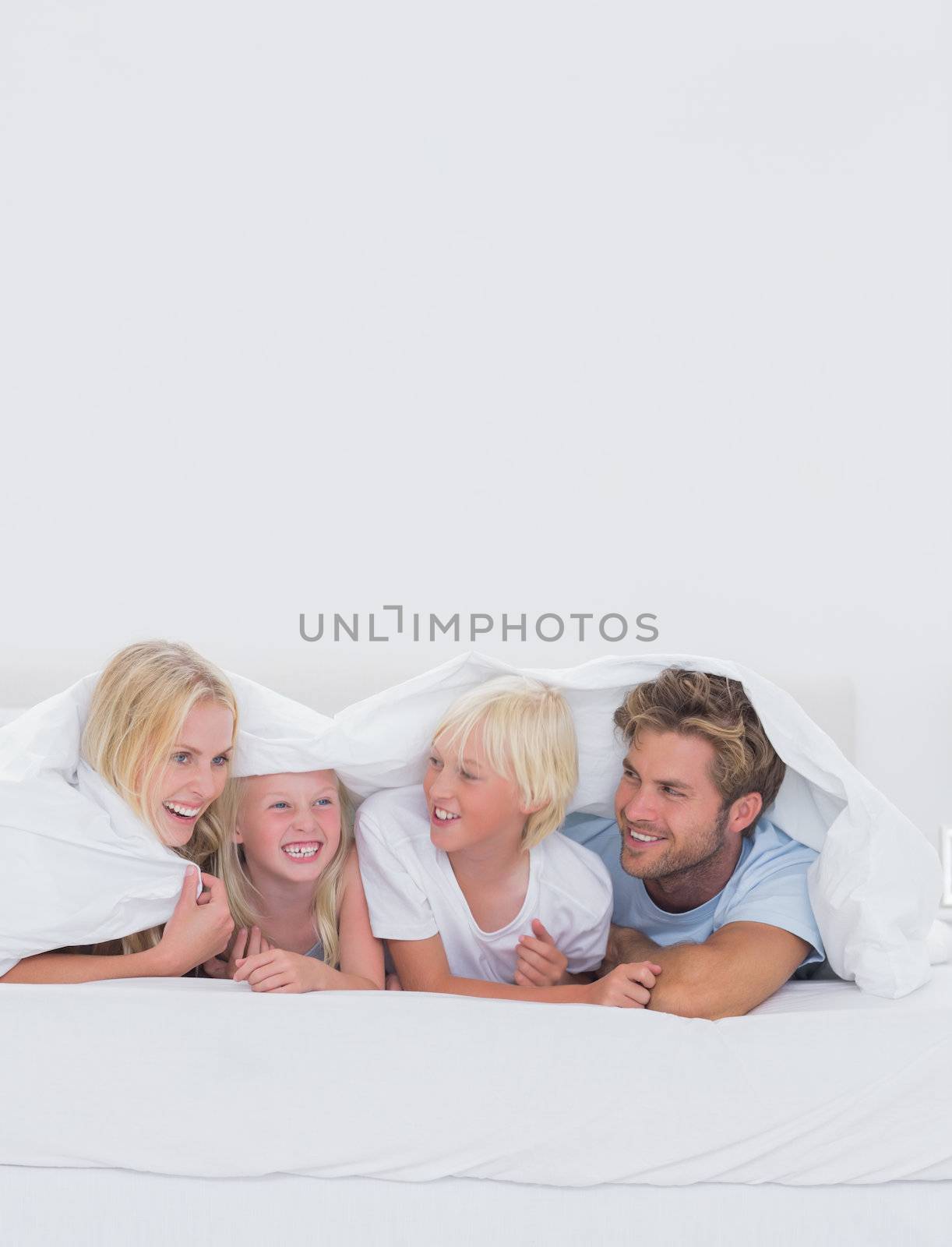 Cheerful family under the duvet at home in bed