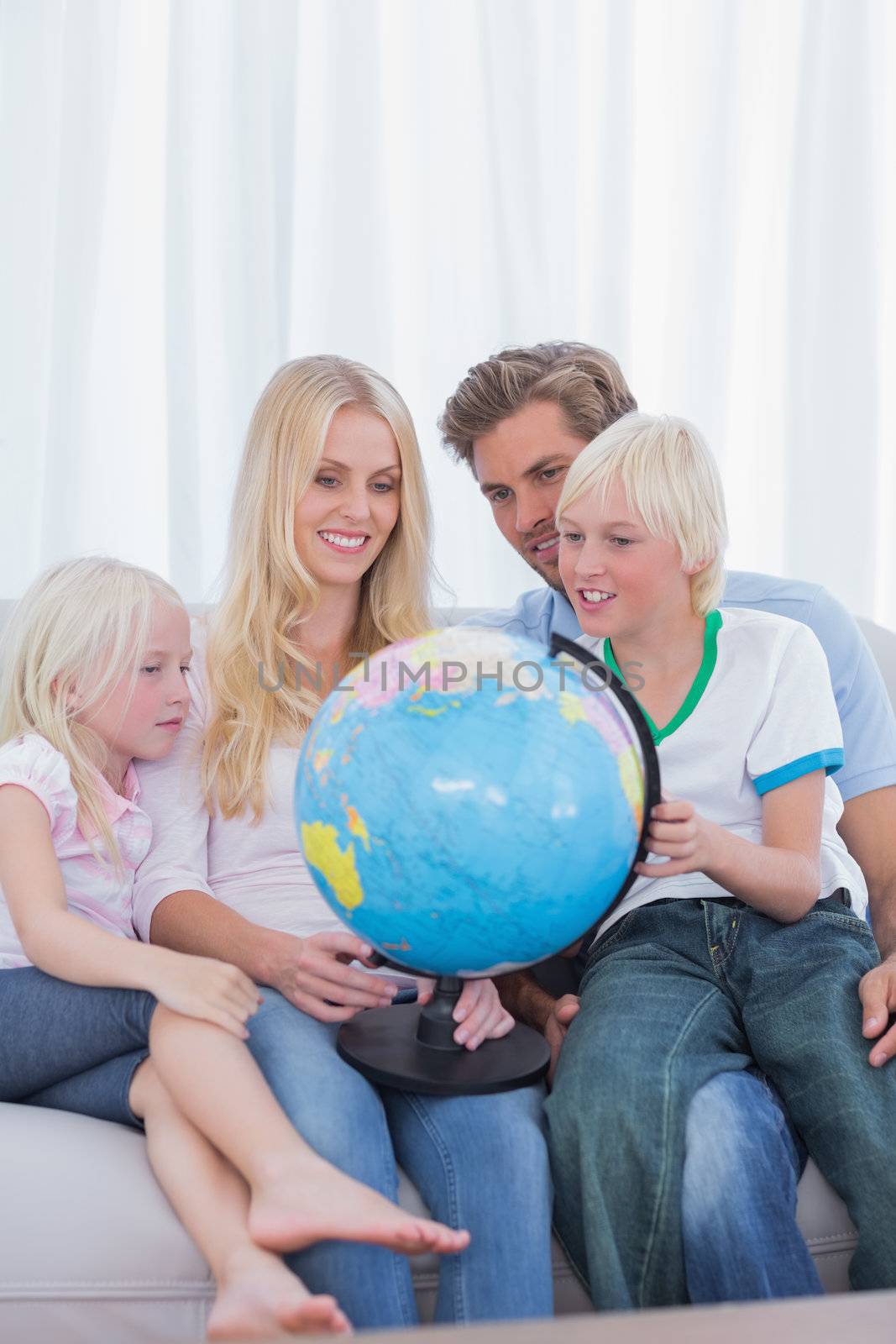Happy family looking at globe on couch by Wavebreakmedia
