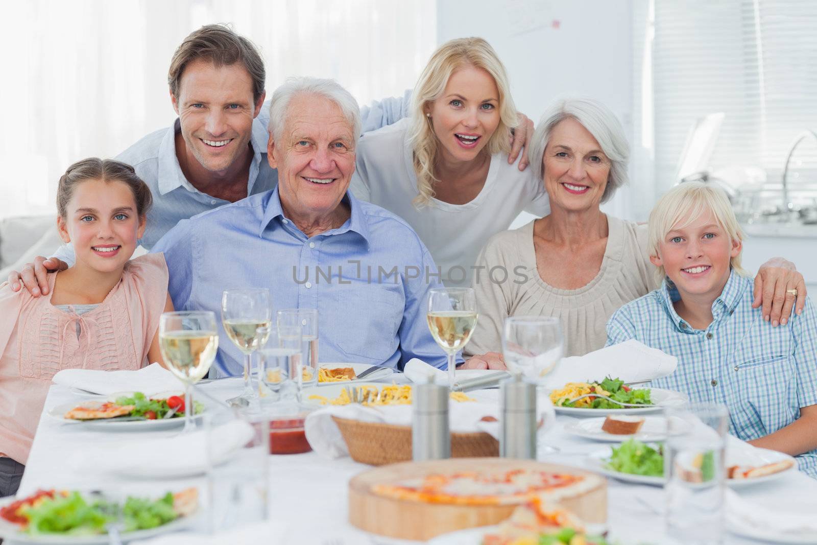 Extended family smiling at dinner family by Wavebreakmedia