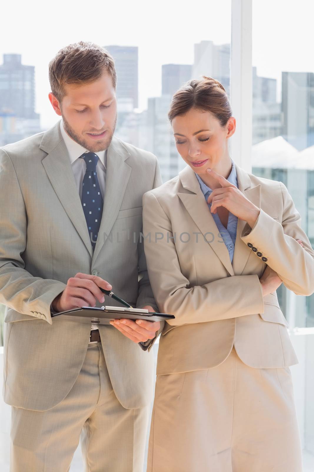 Business people going over document on clipboard in bright office