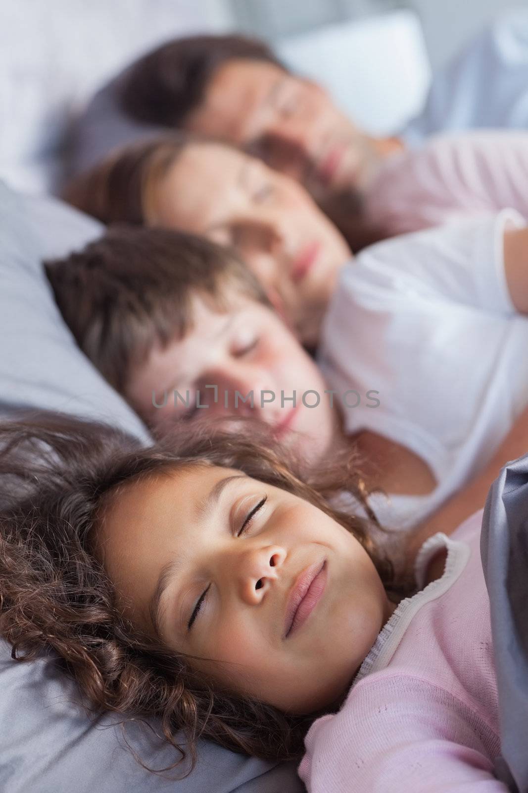 Family sleeping in bed at home