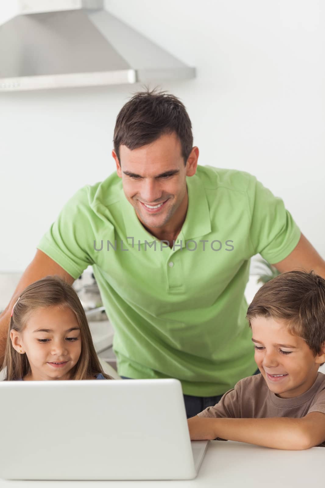 Man and his children using a laptop together in the kitchen