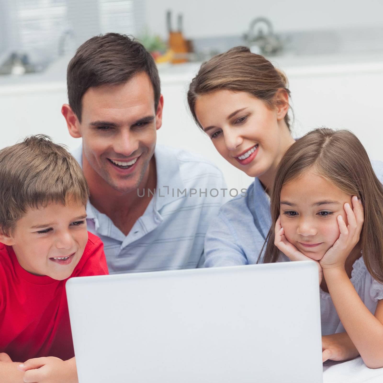 Parents and children using a laptop in the kitchen