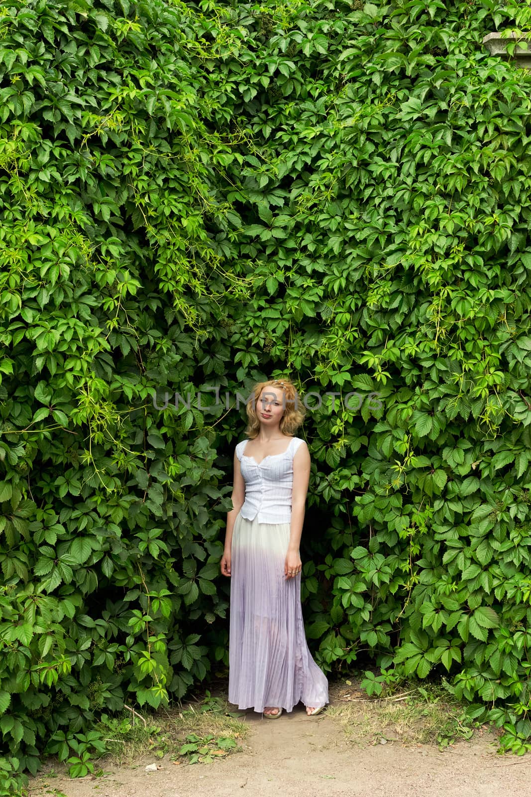 girl in a white dress on a background of leaves