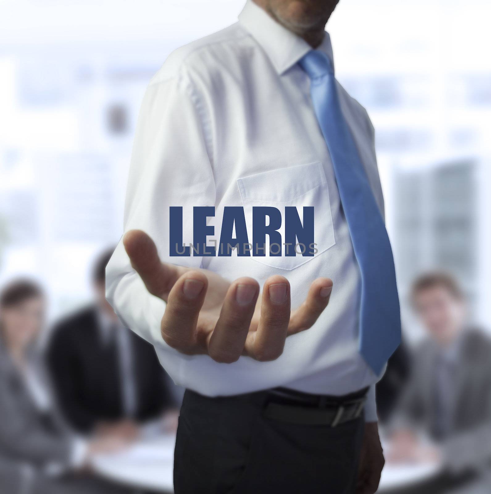 Elegant businessman holding the word learn in front of a business team