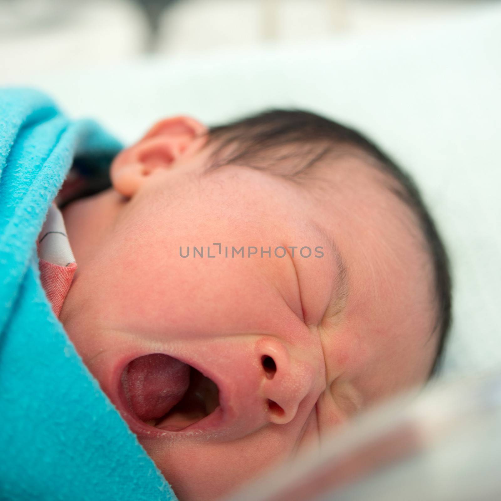 Newborn Asian baby girl yawning in hospital 
