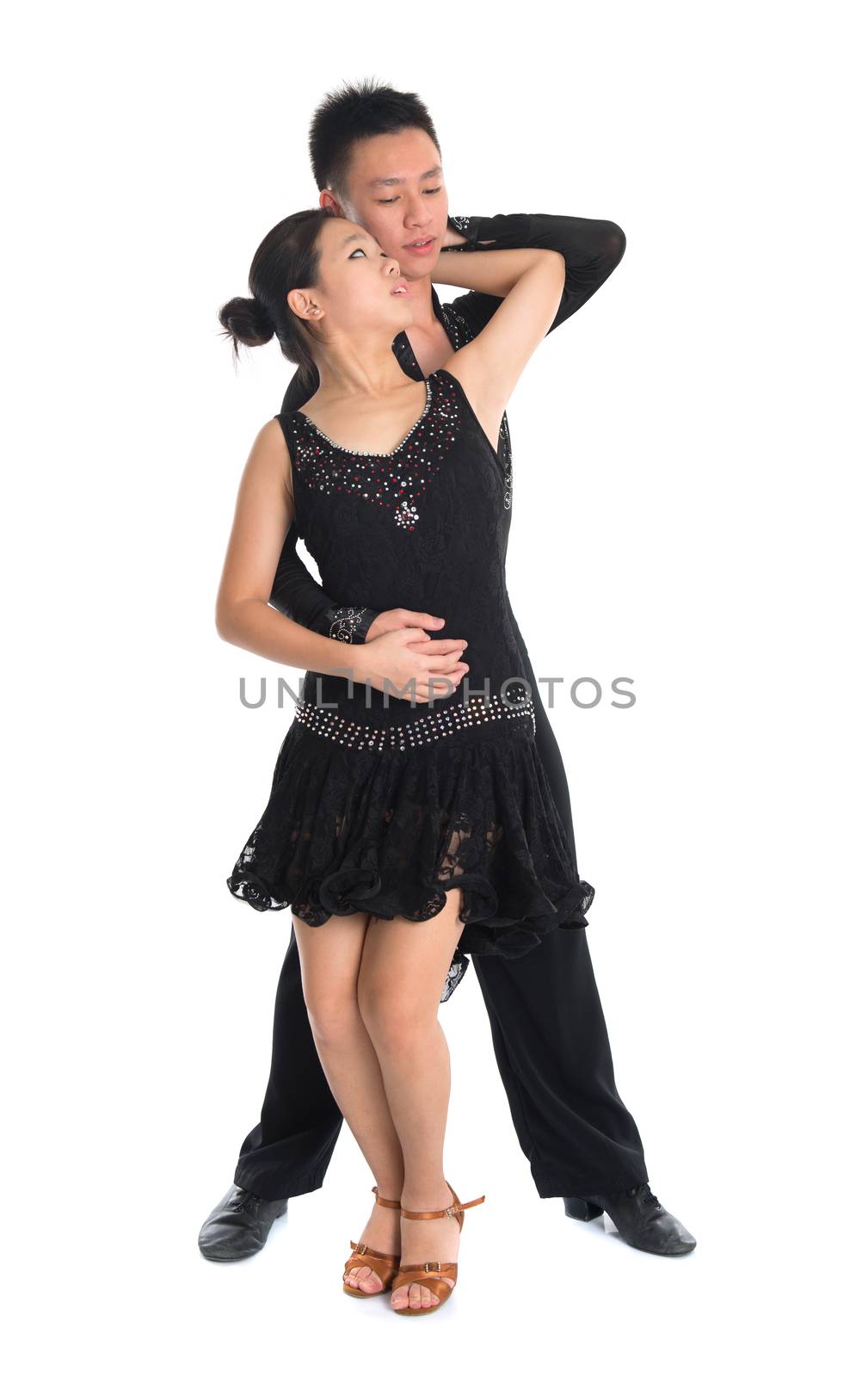 Modern young Asian teens couple latin dancers dancing in front of the studio background, full length isolated white.