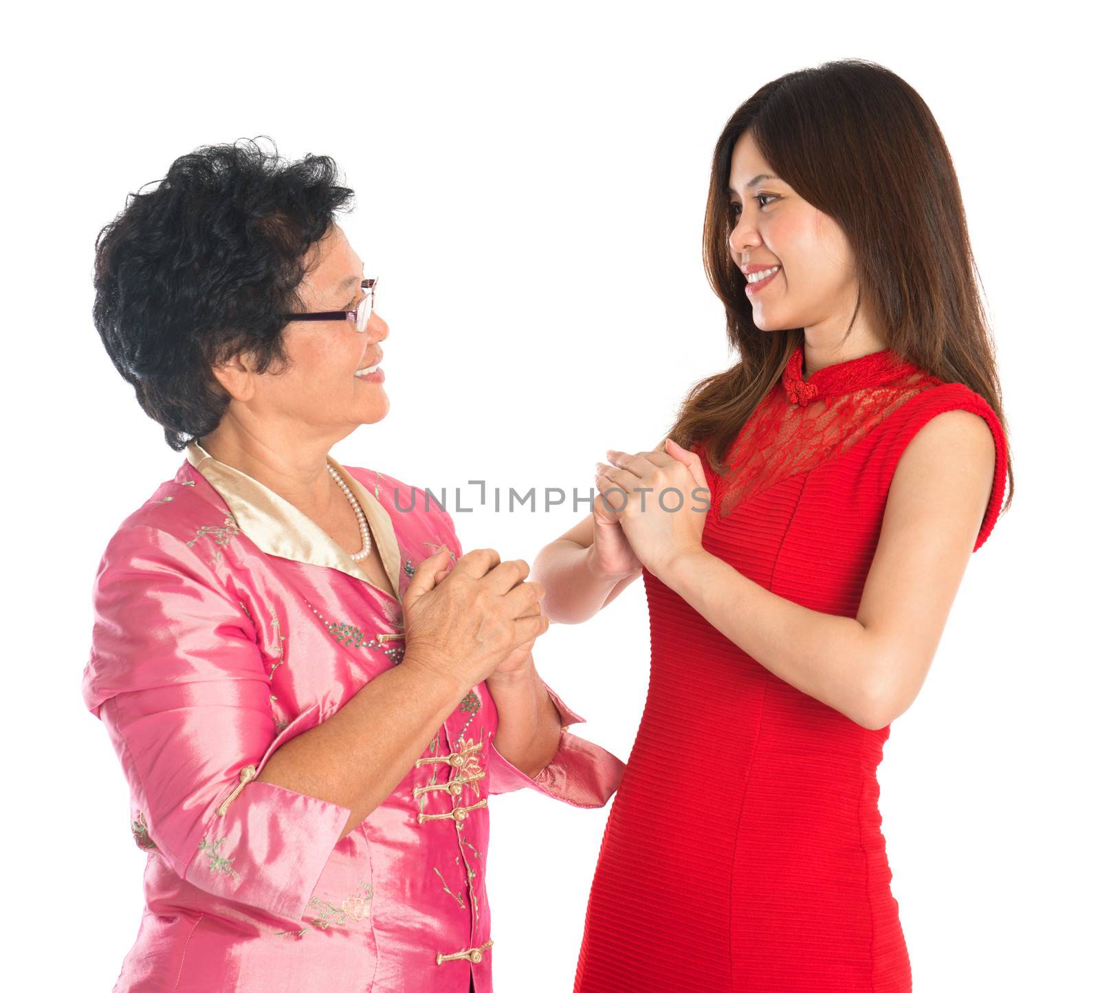 Happy Chinese New Year! Chinese senior parent and daughter in traditional Chinese cheongsam greeting to each other, isolated on white background