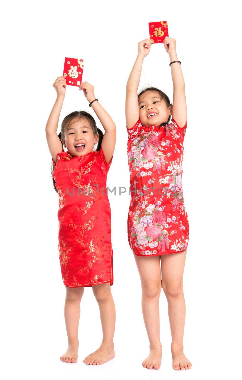 Happy Asian children holding red packet during Chinese New Year, with traditional Cheongsam full length standing isolated on white background.