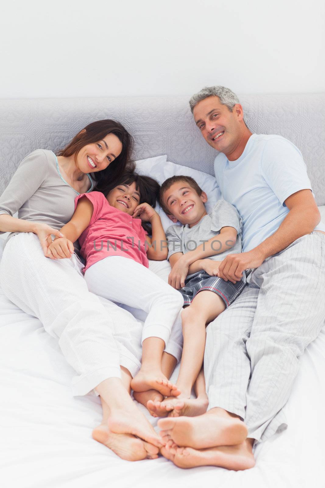 Family lying on bed at home