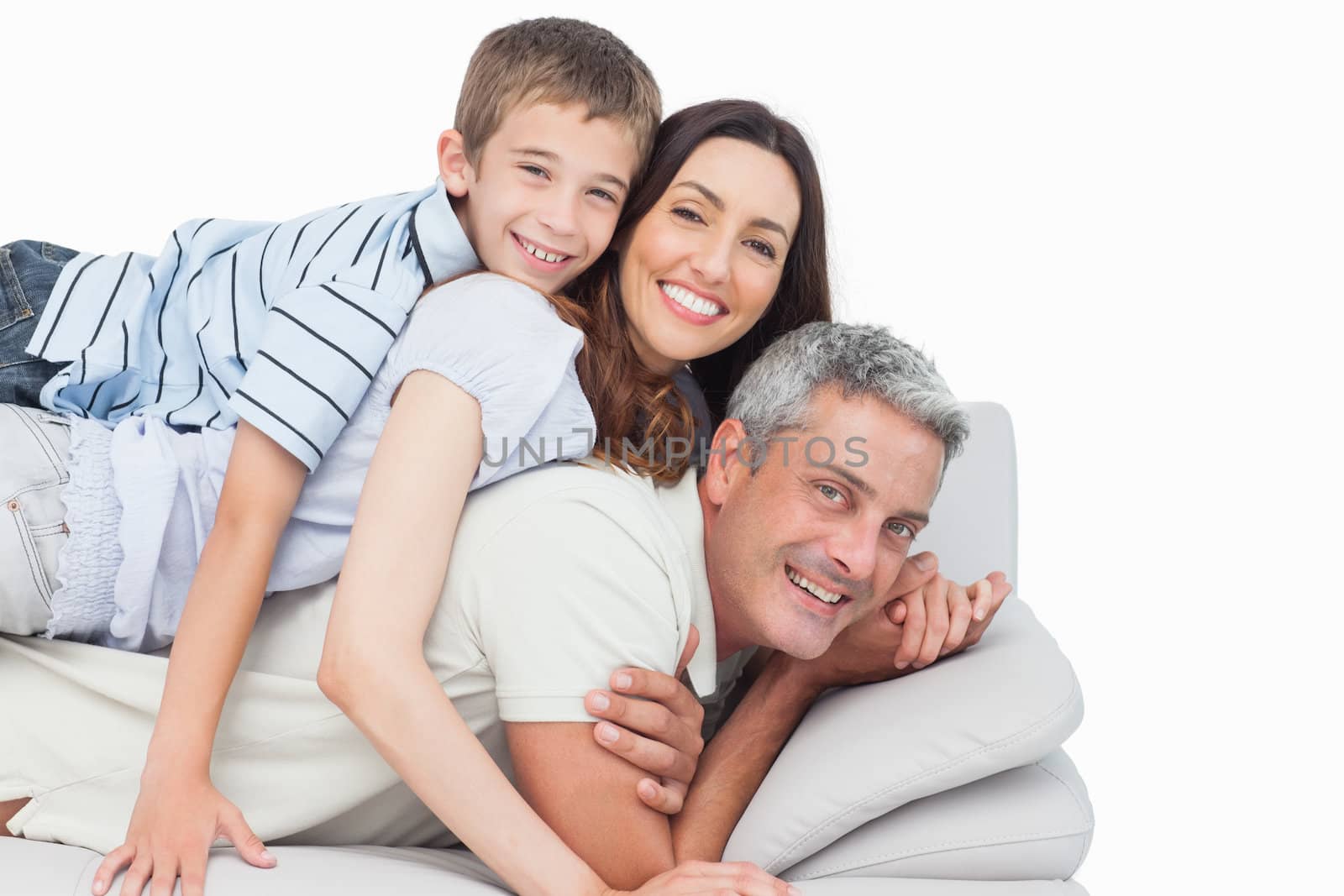 Smiling little boy lying on his parents on sofa on white background