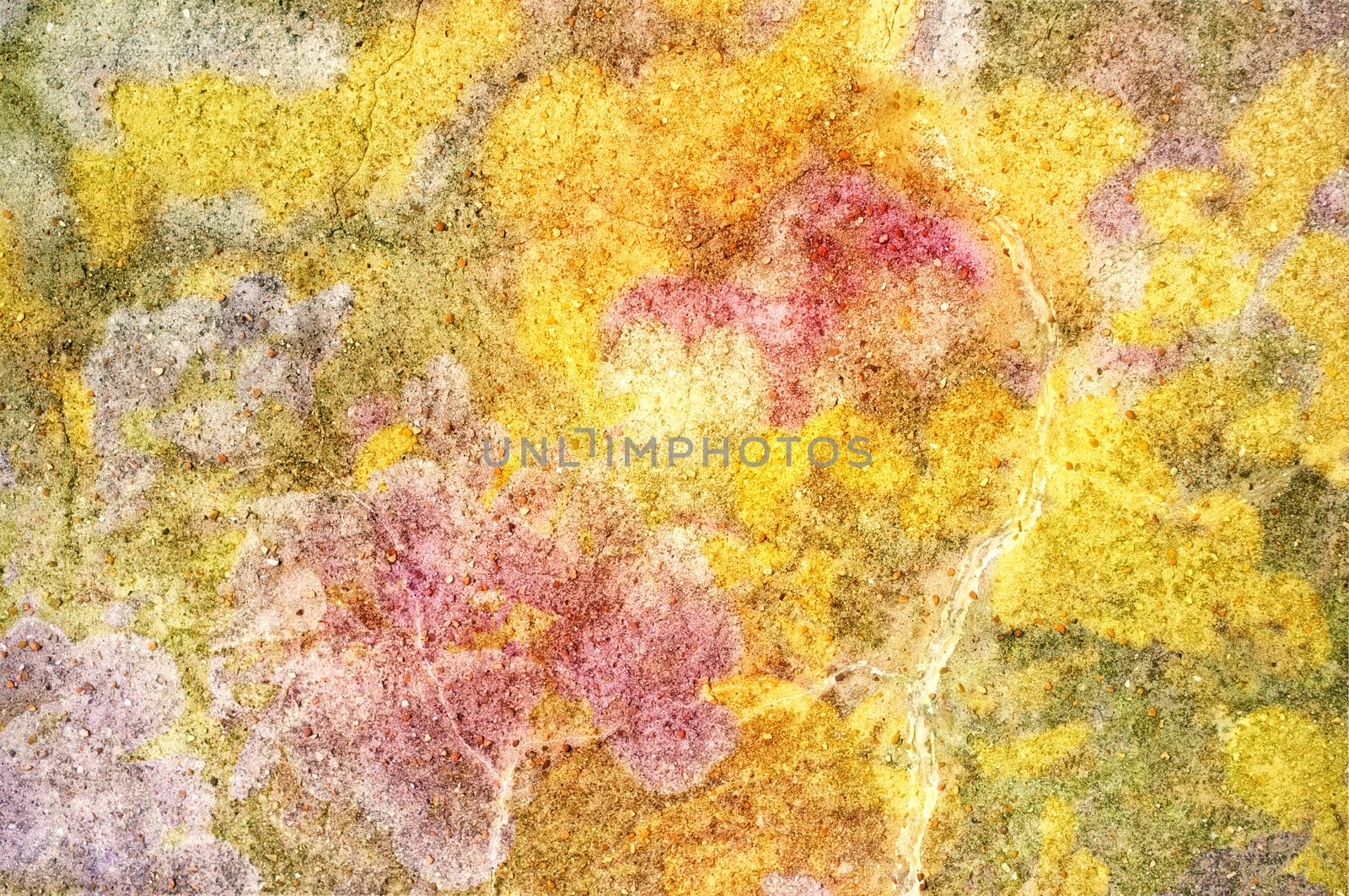 Abstract background texture of a piece of stone, scattered with smaller stones and overlaid with bright yellow, pink and green hues.